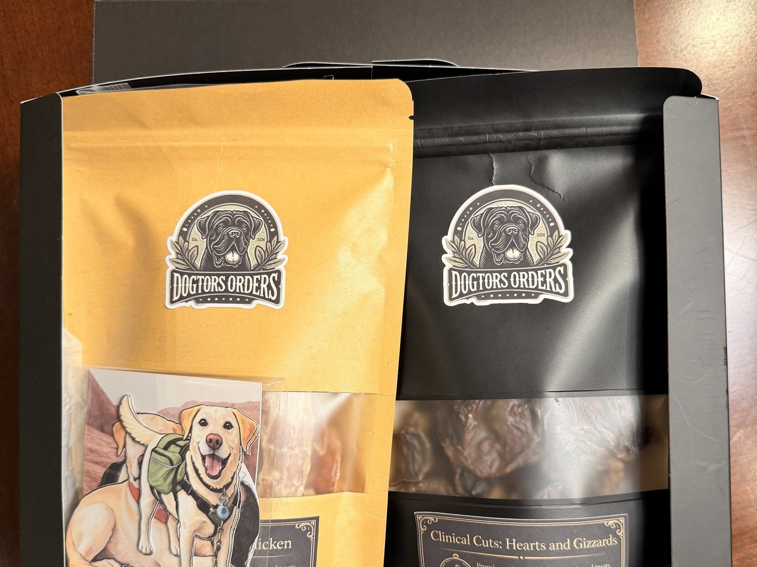 The Dogtors' Gift Box, open — a hand-illustrated Labrador named Diesel on the inside lid, a kraft pouch with a matching illustration card, and the Clinical Cuts Hearts & Gizzards pouch inside